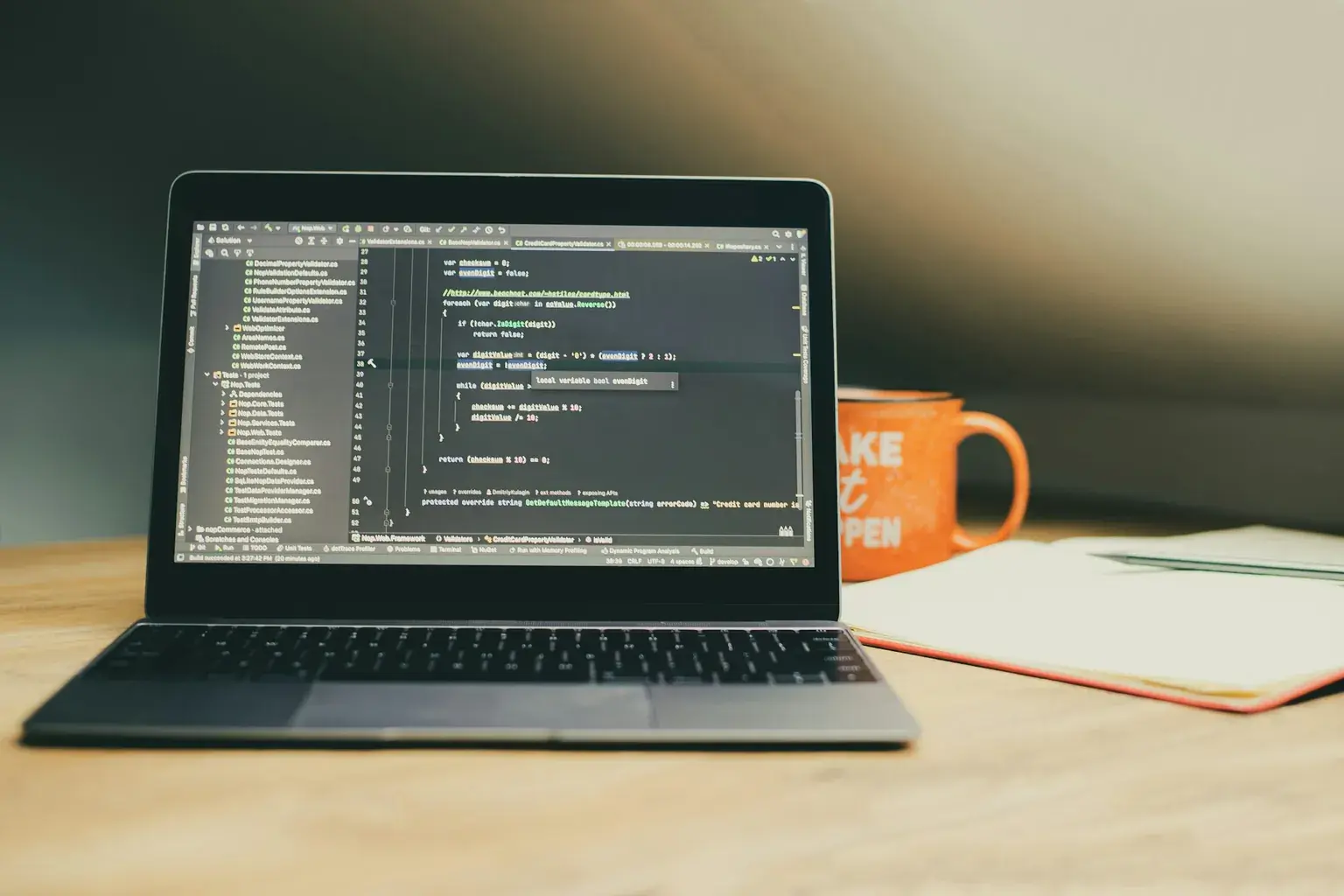 Laptop showing code on a desk beside an orange mug